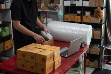 Closeup of man packing parcels with sticky tape at warehouse. Packing products for delivery,...