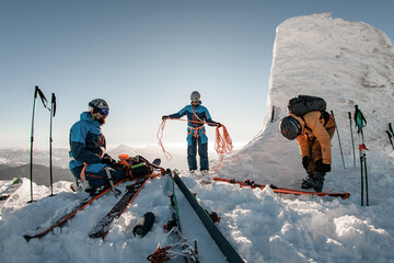 Beautiful view of group of skiers in ski suits and helmets with climbing mountaineering equipment...