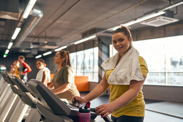 Focus on girl run on treadmill and look at camera