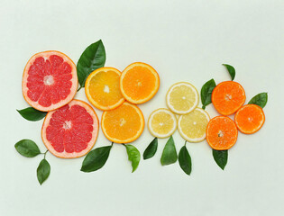 Fototapeta na wymiar Set of fresh citrus fruits slices with green leaves on a light green background. Healthy food photo. Free space for writing .Top view
