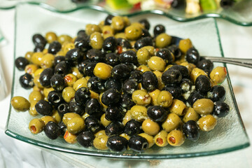 Close-up shot of marinated olives with herbs and spices in wooden plate