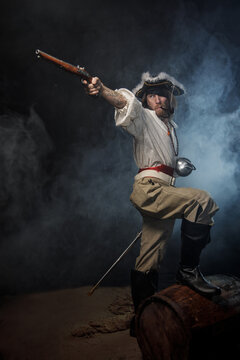 Portrait of pirate filibuster sea robber aiming from old pistol. Concept photo