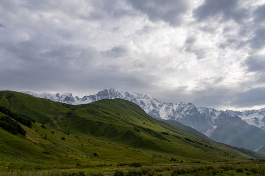Morning sub beams are touching the Chubedishi viewpoint above Ushguli village in the Greater Caucasus Mountain Range in Georgia, Svaneti Region, Ushguli. Snow-capped mountains in the back. Sunrise.