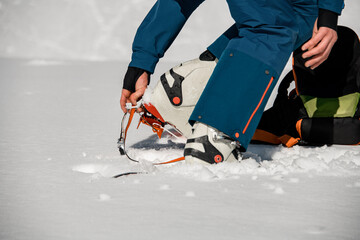 Close-up of leg of man wearing climbing crampons over mountaineering shoes for walking through...
