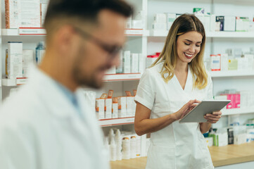 Obraz premium Happy young male and female colleagues pharmacist working in a pharmacy