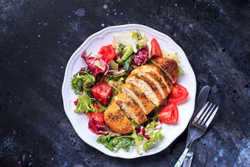Chicken fillet with fresh salad on a white plate. Healthy food concept. Top view, dark background with copy space. Grilled chicken breast.