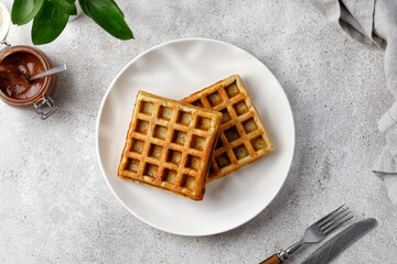 Breakfast waffle on white plate with chocolate paste. Top view
