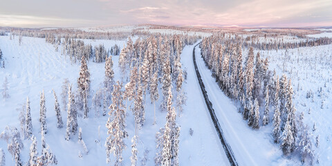 Icy snow covered winter road in the Arctic Circle at sunset in Lapland, Finland