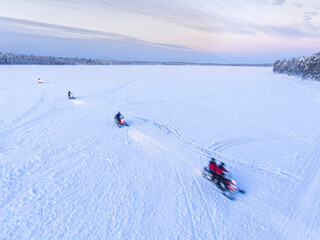 Snow mobiles on a snow mobiling adventure on a snow covered frozen lake in winter at Finnish...
