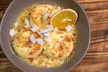 Cottage cheese fritters or Syrniki served with orange and coconuts. Ukrainian, Russian food.