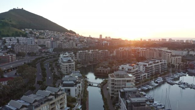 Aerial shot flying towards the marina island in Cape Town as the sun is about to dip over the horizon.