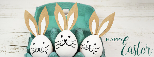 Happy Easter background banner panorama greeting card -Close-up from white painted eggs and easter bunny in green turquoise egg carton on rustic white vintage shabby wooden table