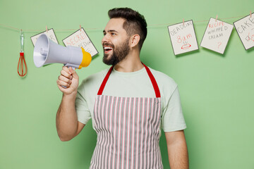 Young male chef confectioner baker man in striped apron hold scream in megaphone announces...