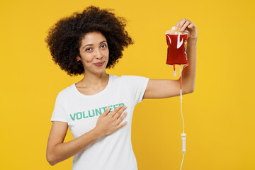 Young donor woman of African American ethnicity wears white volunteer t-shirt hold bag with blood...