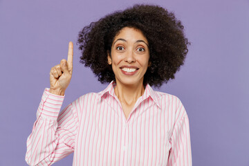 Young insighted fun woman of African American ethnicity 20s wear pink white striped shirt holding...