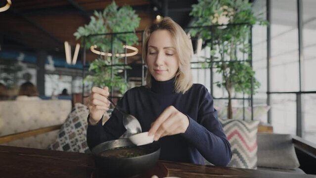 Attractive blonde in a restaurant. A woman eats pan-Asian soup.