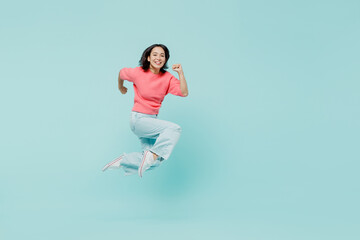 Full body young smiling happy woman of Asian ethnicity 20s wear pink sweater jump high run fast hurry up isolated on pastel plain light blue color background studio portrait. People lifestyle concept.