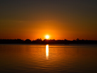Reflexo do sol dourado na água. Vista através da margem da lagoa.