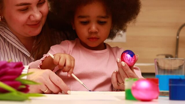 multiethnic family preparing to easter event at kitchen painting eggs