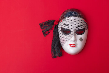 Porcelain venetian mask on red wall with copy space