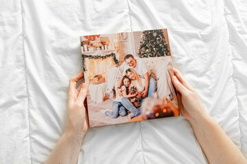a hands holds a book with photos of mom, dad and daughter in the photo studio.