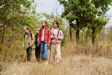 Multiracial four teenagers hiking in autumn forest