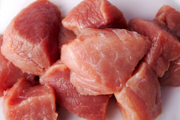 Sliced pieces of raw red meat ready for cooking on a white isolated background close-up