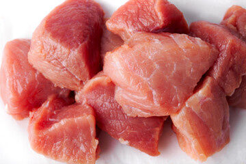 Sliced pieces of raw red meat ready for cooking on a white isolated background close-up