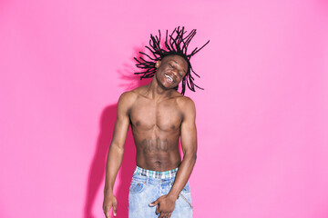 Black shirtless man with dreadlocks laughing and dancing