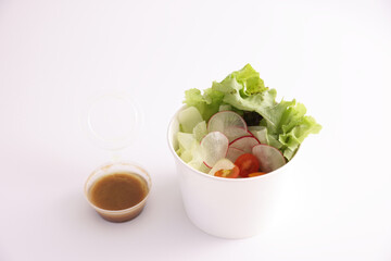 Salad in plastic package for take away or food delivery isolated on white background