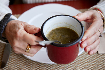 Woman's hands with a cup of broth of turnip greens. This dish is typical of the gastronomy of Galicia (Spain)