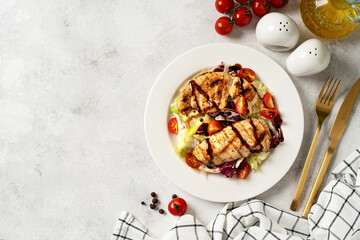 Grilled chicken fillet with vegetables in a white plate on a light gray culinary background. Dietary poultry breast on the kitchen table	