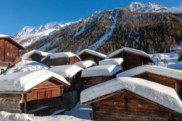 Toits enneigés d'un village de montagne dans les Alpes valaisannes, Suisse - 485825071