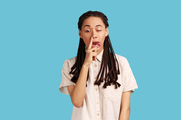 Portrait of funny impolite woman with black dreadlocks making crazy face with tongue out and...