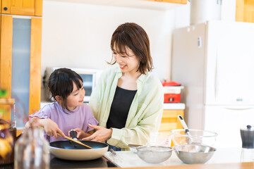 お母さんと一緒に料理をする小さな女の子