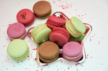 Assorted french macarons. Small French pastries on a plate in the form of a star. Macarons with pistachio, chocolate, raspberry and strawberry flavors