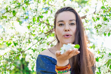 Happy brunette woman in blooming garden holding flowers