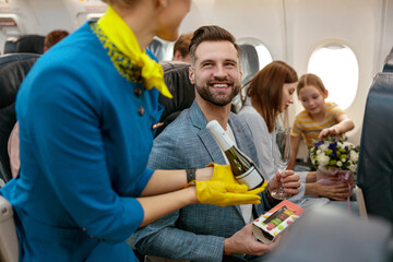 Flight attendant giving champagne to man in airplane