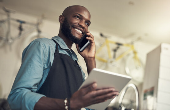 Im calling to let you know youre bike is ready. Shot of a handsome young man standing alone in his bicycle shop and using technology.