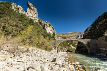 Joli et charmant ancien pont de pierres formant une arche sur une rivière émeraude dans une gorge...