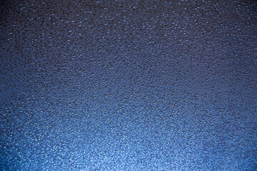 Water drops on a blue surface with selective focus.