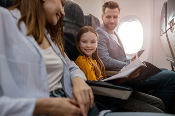 Joyful little girl traveling with parents on airplane