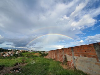 Double rainbow landscape. Clouded sky with rainbows. Small city meadow in the morning after the storm.