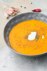 Pumpkin and carrot soup with cream on a gray background. Top view.	