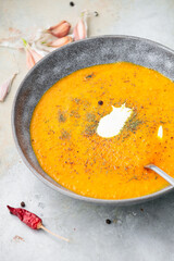 Pumpkin and carrot soup with cream on a gray background. Close up shot