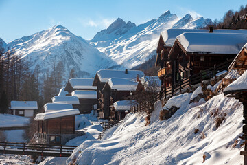 Village avec ses traditionnels chalets de bois au pied des montagnes du Valais, Suisse - 485832463