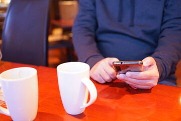Obraz na płótnie Canvas Man using smartphone at cafe, texting on his mobile phone - スマートフォン 操作する男性 