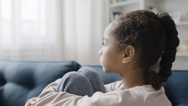 Upset child sitting on the sofa, waiting for parents, thinking of school trouble - Powered by Adobe