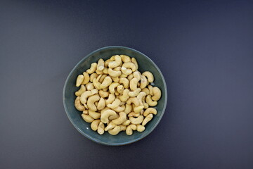 Cashew nuts in a round bowl on a gray background. Top view, copy space for text. Healthy snack, vegetarian food. 