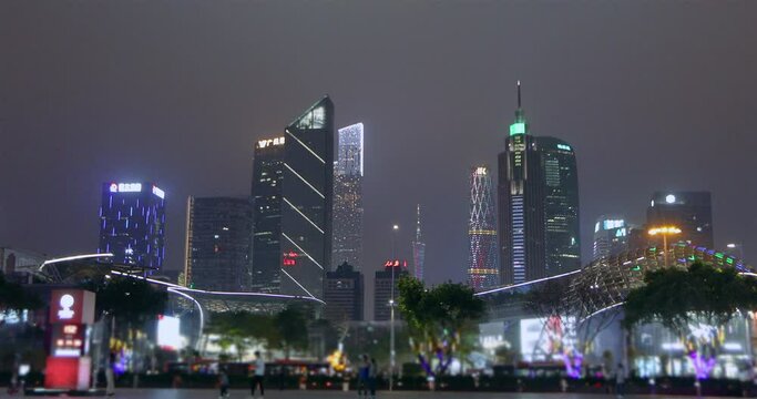 Large building illuminated by neon. Night Guangzhou, people walk through the night city